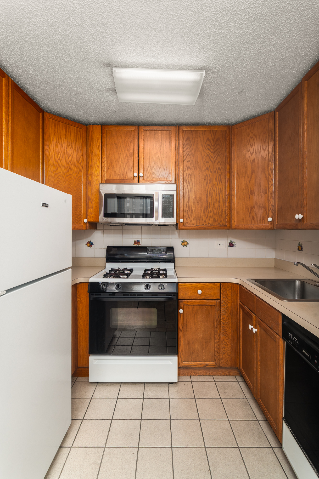 77 Fulton Street, Unit 18G Manhattan, NY 10038 - Photo 5 of 8 a kitchen with a stove a sink and a refrigerator