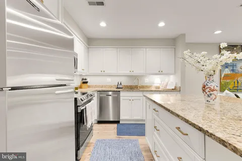 a kitchen with stainless steel appliances granite countertop a sink a stove and a refrigerator