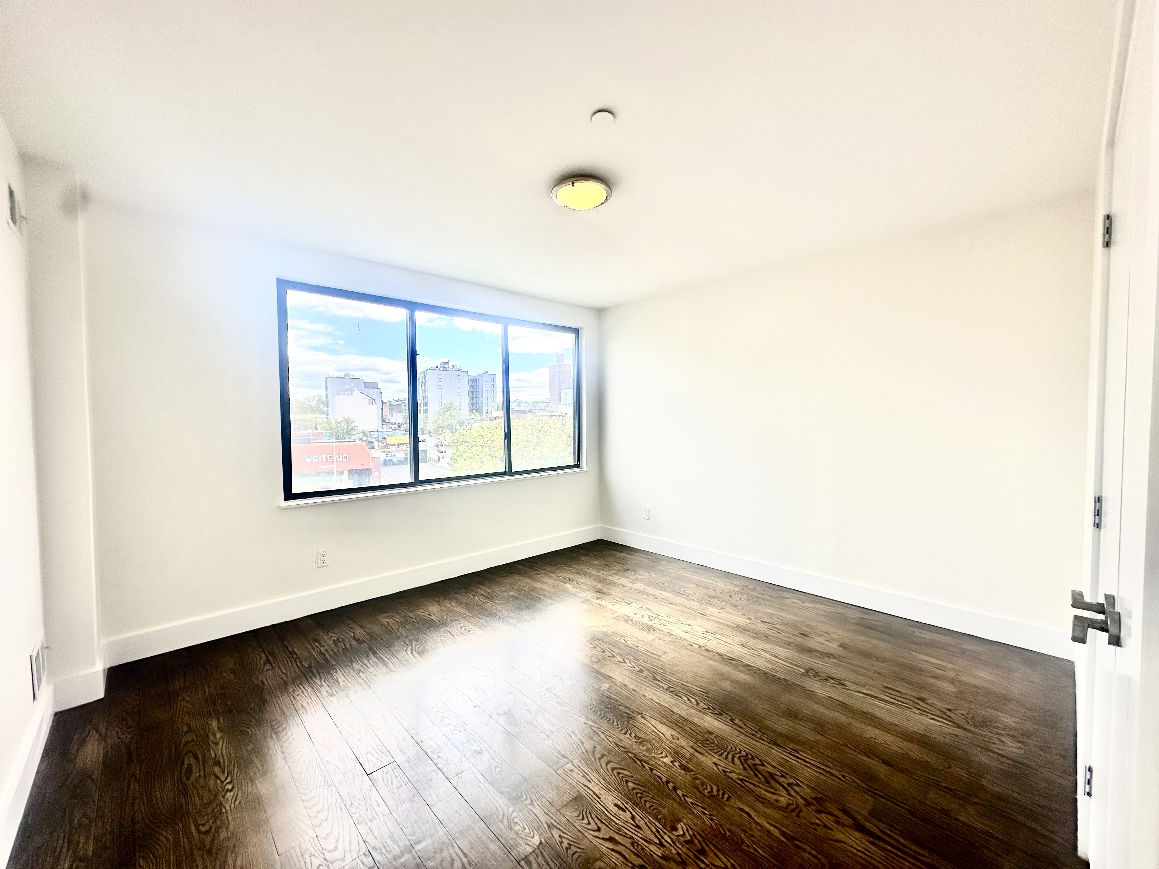 29 MacDougal Street, Unit 2 Brooklyn, NY 11233 - Photo 10 of 14 an empty room with wooden floor and windows
