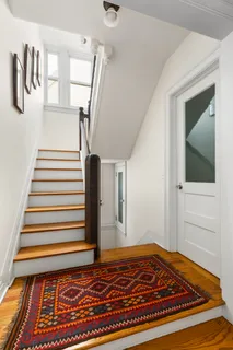 a view of a hallway with wooden floor and stairs