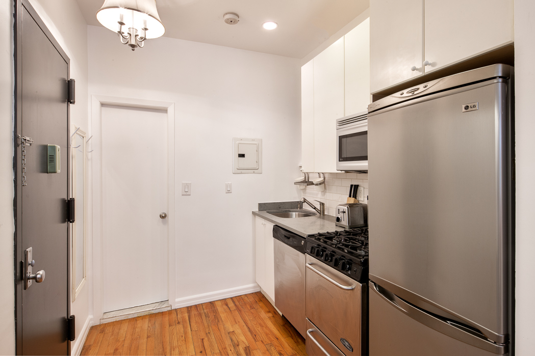 237 East 88th Street, Unit 103 Manhattan, NY 10128 - Photo 2 of 3 a kitchen with a refrigerator and a sink