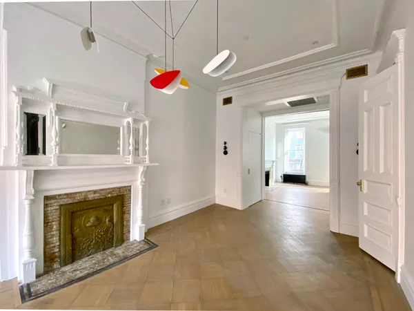 a view of a livingroom with wooden floor a fireplace and entryway