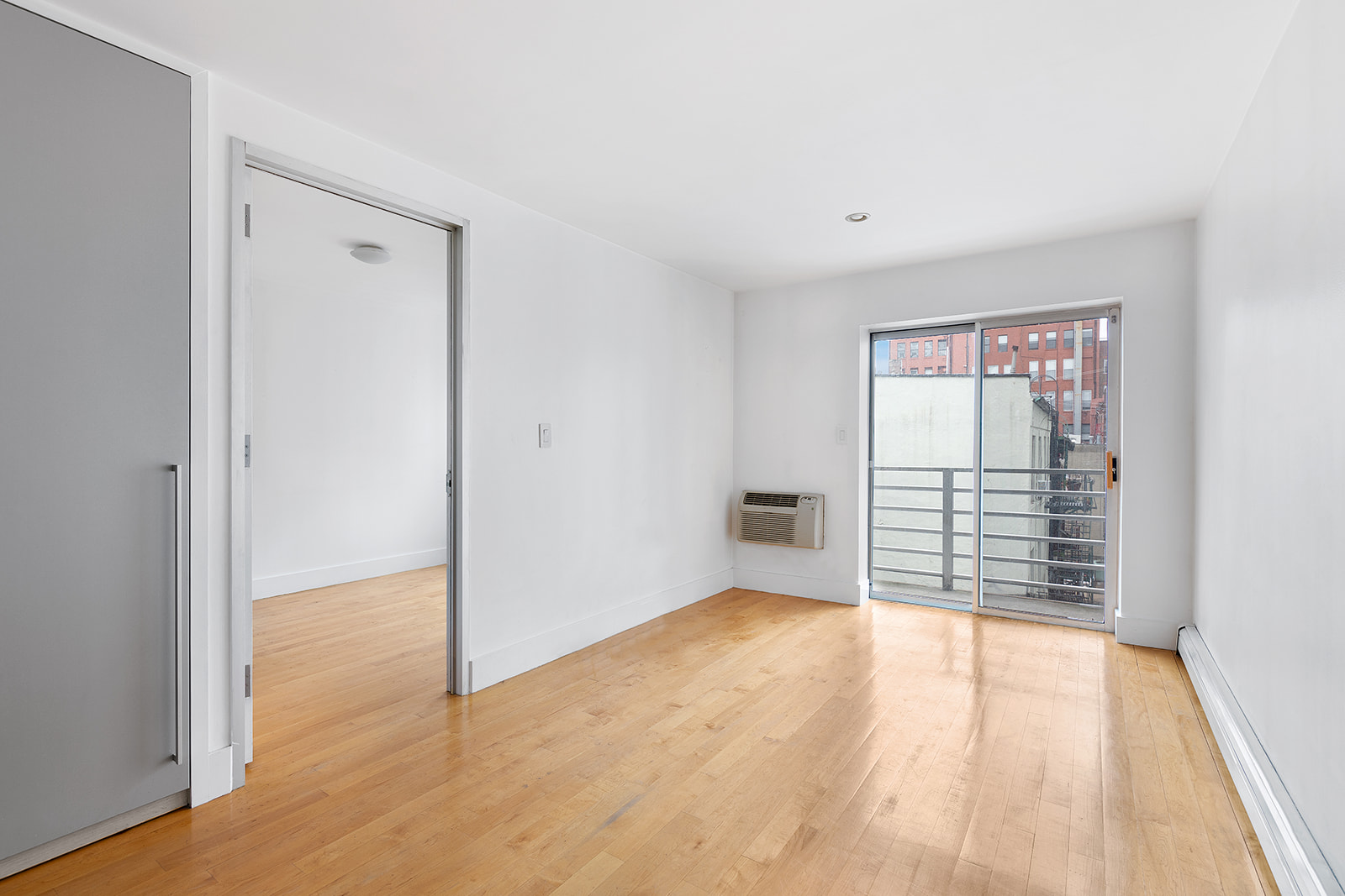 181 Hester Street, Unit 4A Manhattan, NY 10013 - Photo 2 of 8 a view of an empty room with wooden floor and a window
