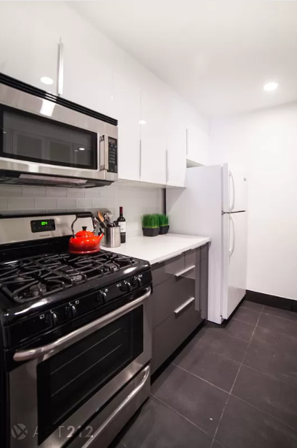 179 Grand Street, Unit 2F Manhattan, NY 10013 - Photo 4 of 13 a kitchen with stainless steel appliances and white cabinets