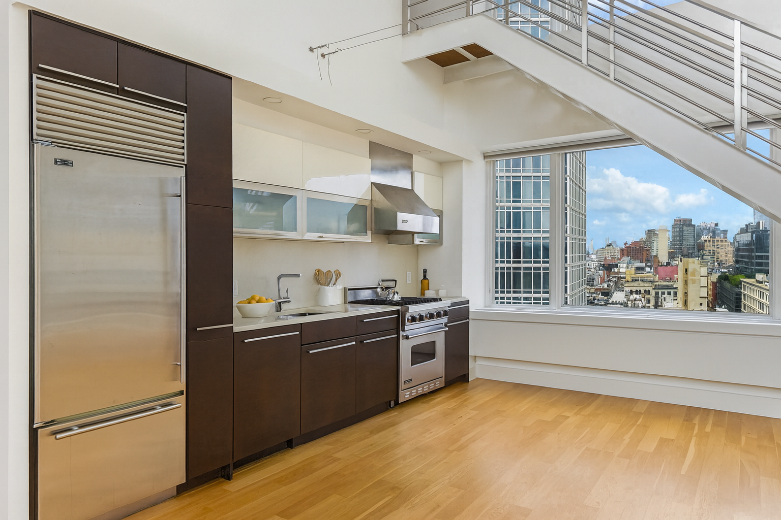 161 Grand Street, Unit PHB Manhattan, NY 10013 - Photo 4 of 11 a kitchen with stainless steel appliances granite countertop a refrigerator a sink dishwasher a stove and a dining table with wooden floor