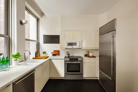 a kitchen with stainless steel appliances a refrigerator sink and white cabinets