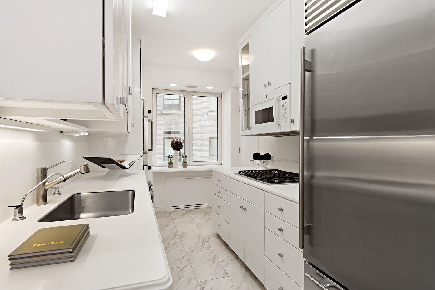 900 5th Avenue, Unit 4B Manhattan, NY 10021 - Photo 8 of 14 a kitchen with white cabinets and a sink
