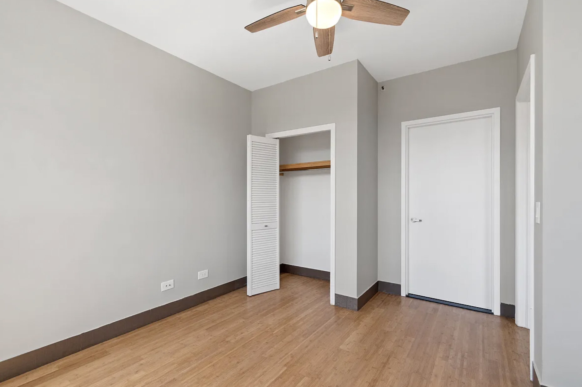 5-43 48th Avenue, Unit 5E Queens, NY 11101 - Photo 7 of 9 an empty room with wooden floor fan and windows