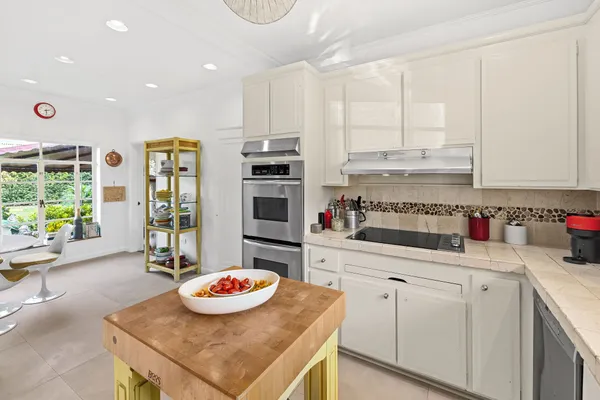 a kitchen with stainless steel appliances kitchen island granite countertop a sink and white cabinets