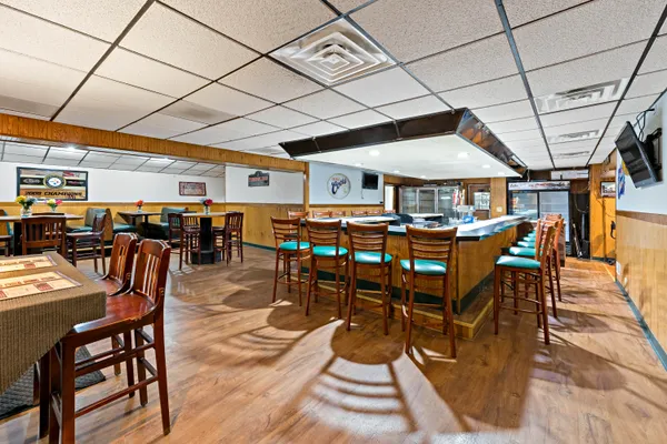 a dining hall with stainless steel appliances kitchen island granite countertop a dining table and chairs with wooden floor