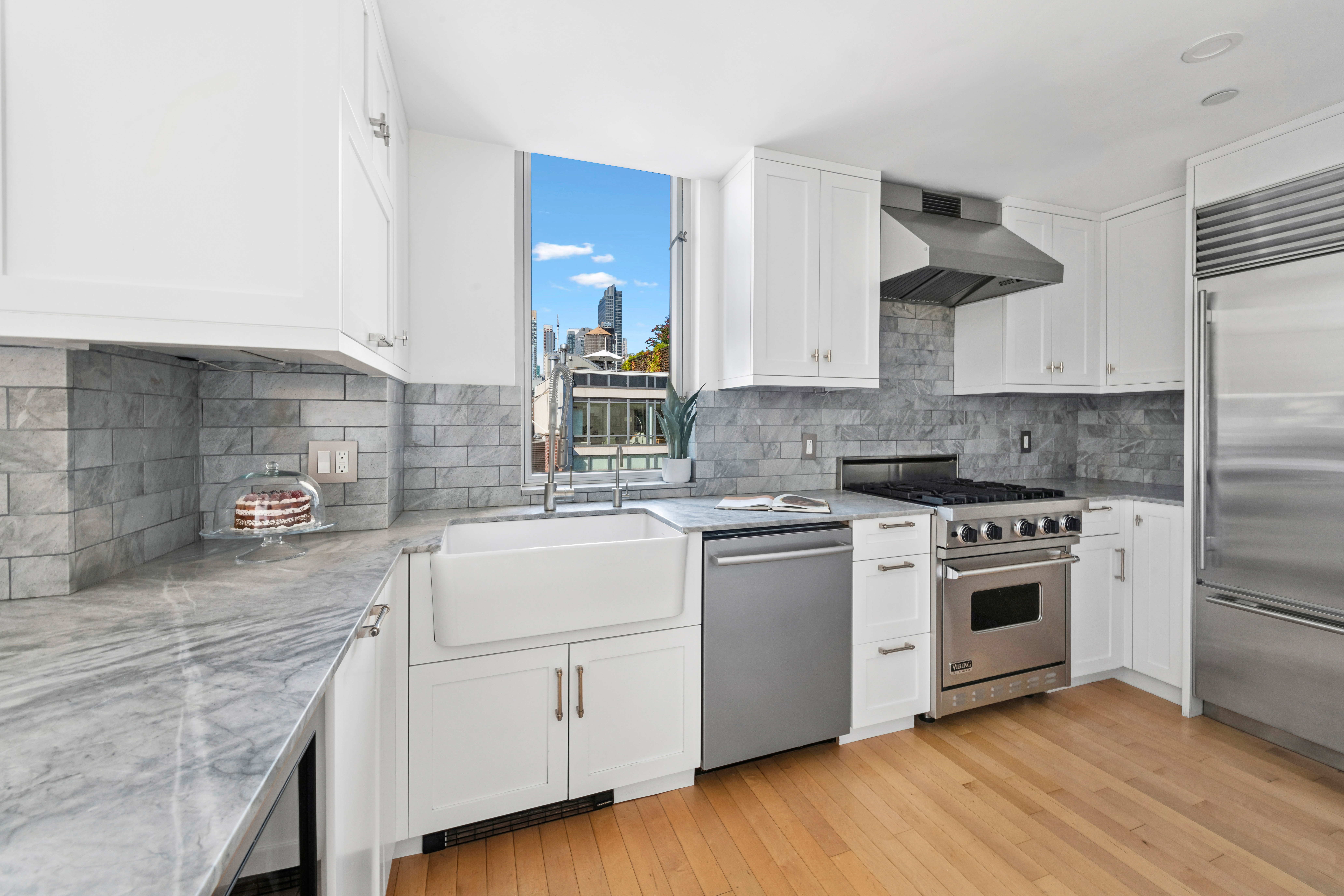 146-148 West 22nd Street, Unit PH Manhattan, NY 10011 - Photo 4 of 13 a kitchen with white cabinets stainless steel appliances and sink