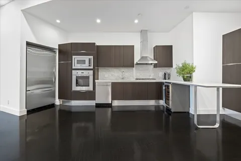 a kitchen with stainless steel appliances wooden floor and a sink