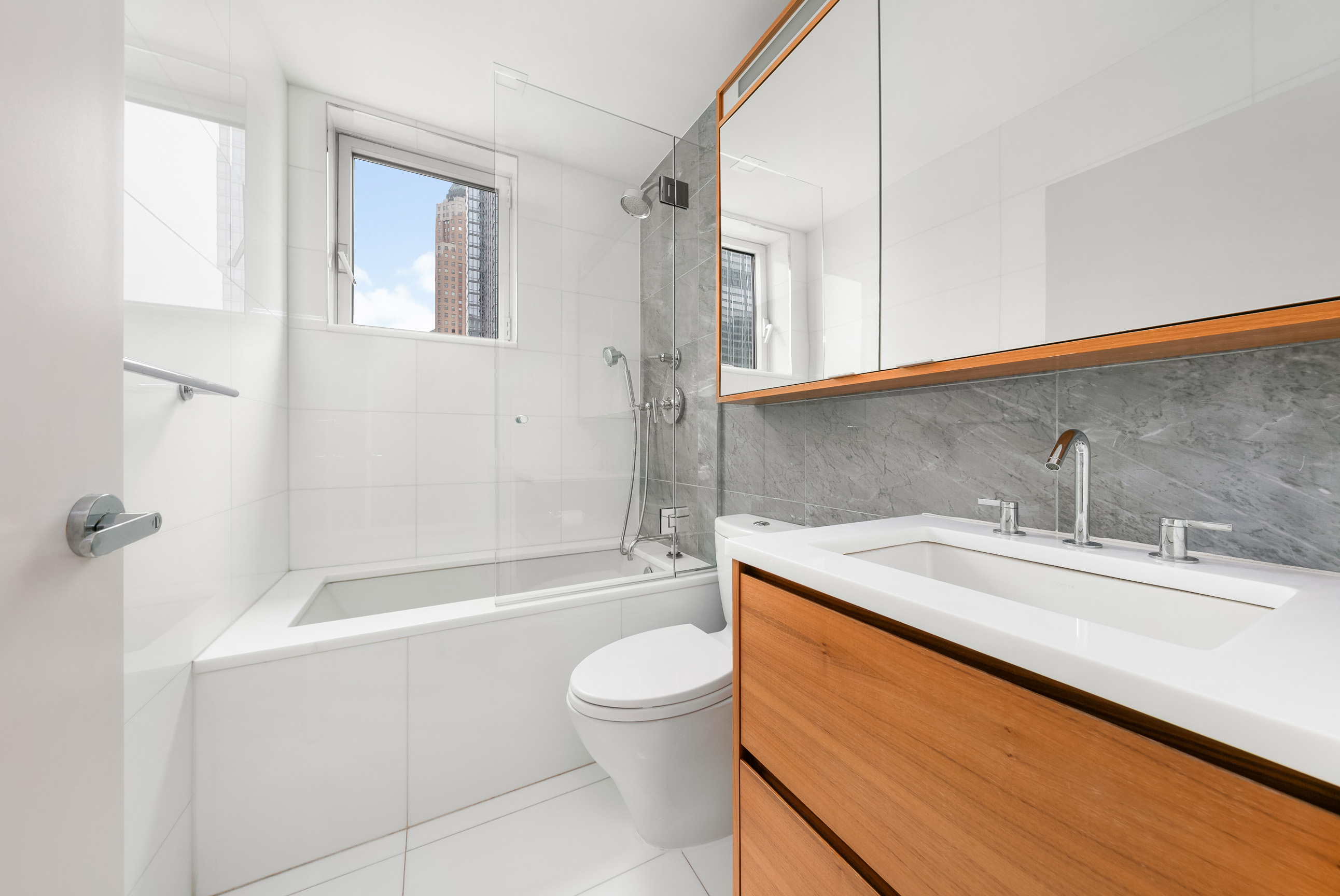 301 West 53rd Street, Unit 19K Manhattan, NY 10019 - Photo 7 of 8 a bathroom with a granite countertop sink toilet and shower