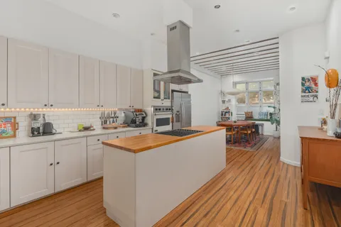 a large white kitchen with wooden floors and stainless steel appliances