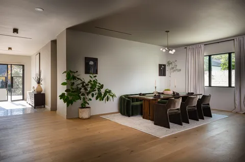 a view of a white house next to a yard with big trees