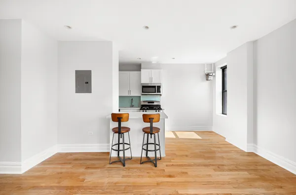 a living room with stainless steel appliances furniture a refrigerator and wooden floor