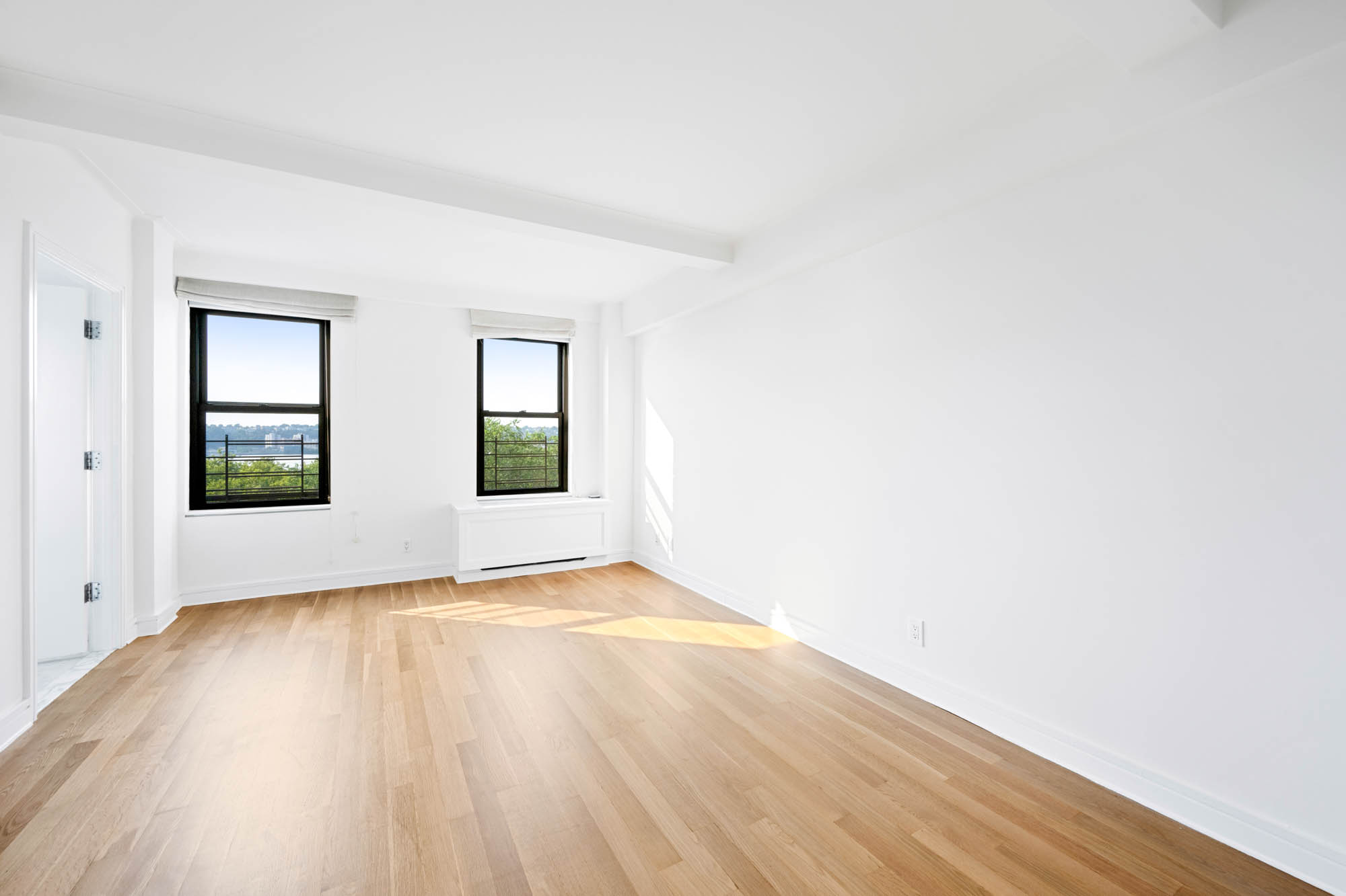 230 Riverside Drive, Unit 8D Manhattan, NY 10025 - Photo 8 of 19 a view of an empty room with window and wooden floor
