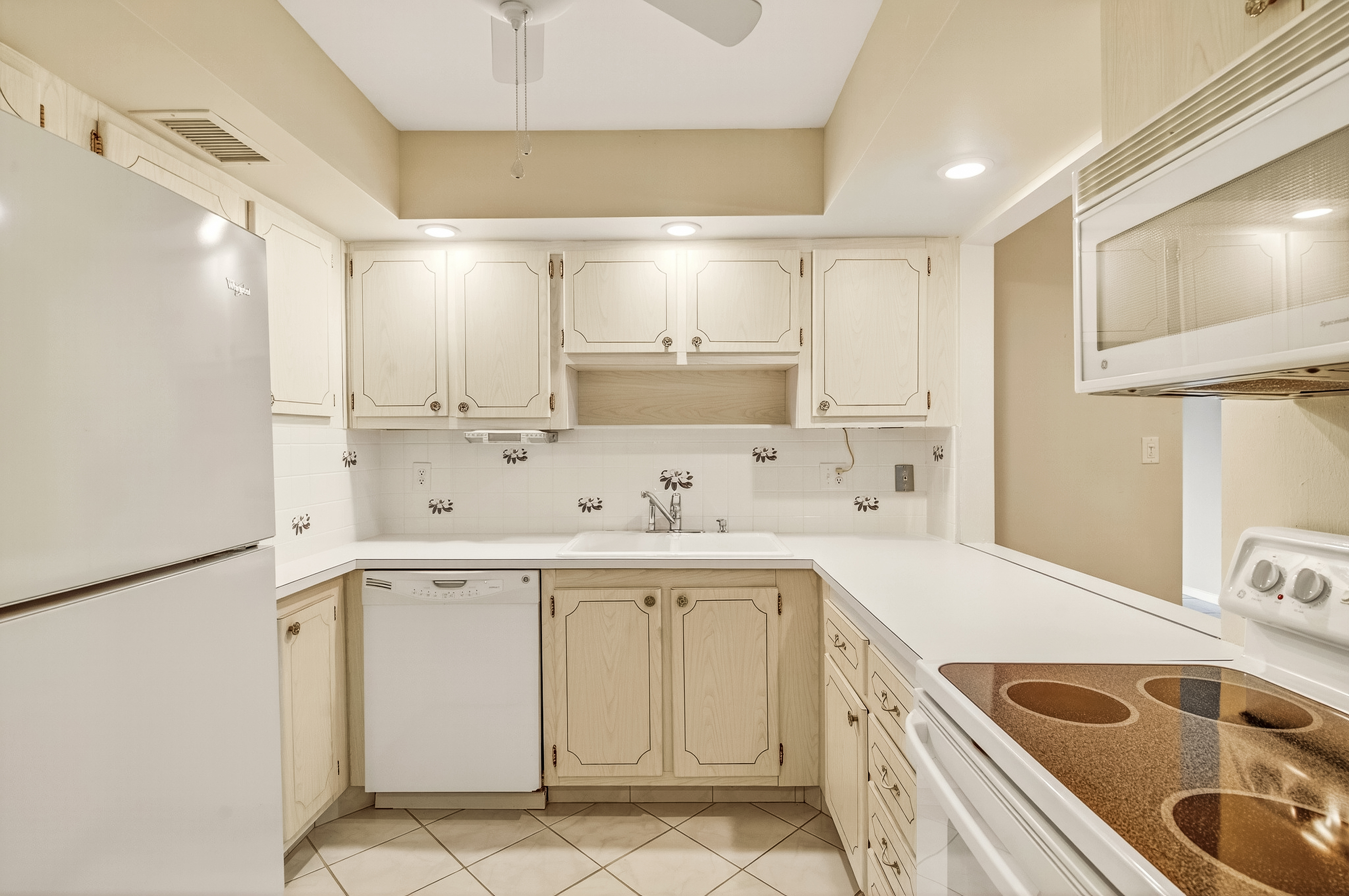 4601 Highway A1a, Unit 102 Vero Beach, FL 32963 - Photo 9 of 29 a kitchen with a sink a stove a refrigerator and white cabinets with wooden floor