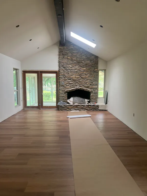 an empty room with windows and fireplace