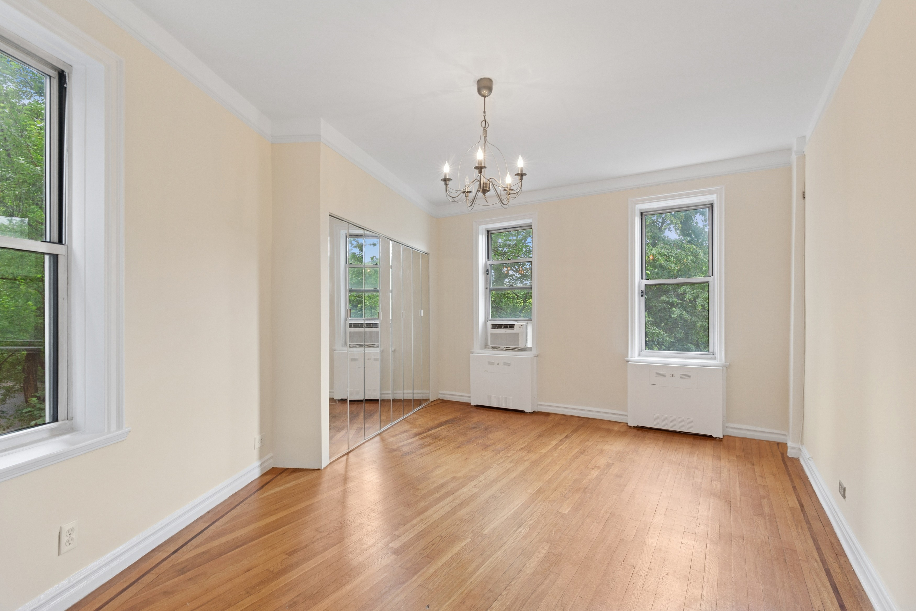 585 West 214th Street, Unit 4G Manhattan, NY 10034 - Photo 9 of 18 an empty room with wooden floor windows and exposed bricks