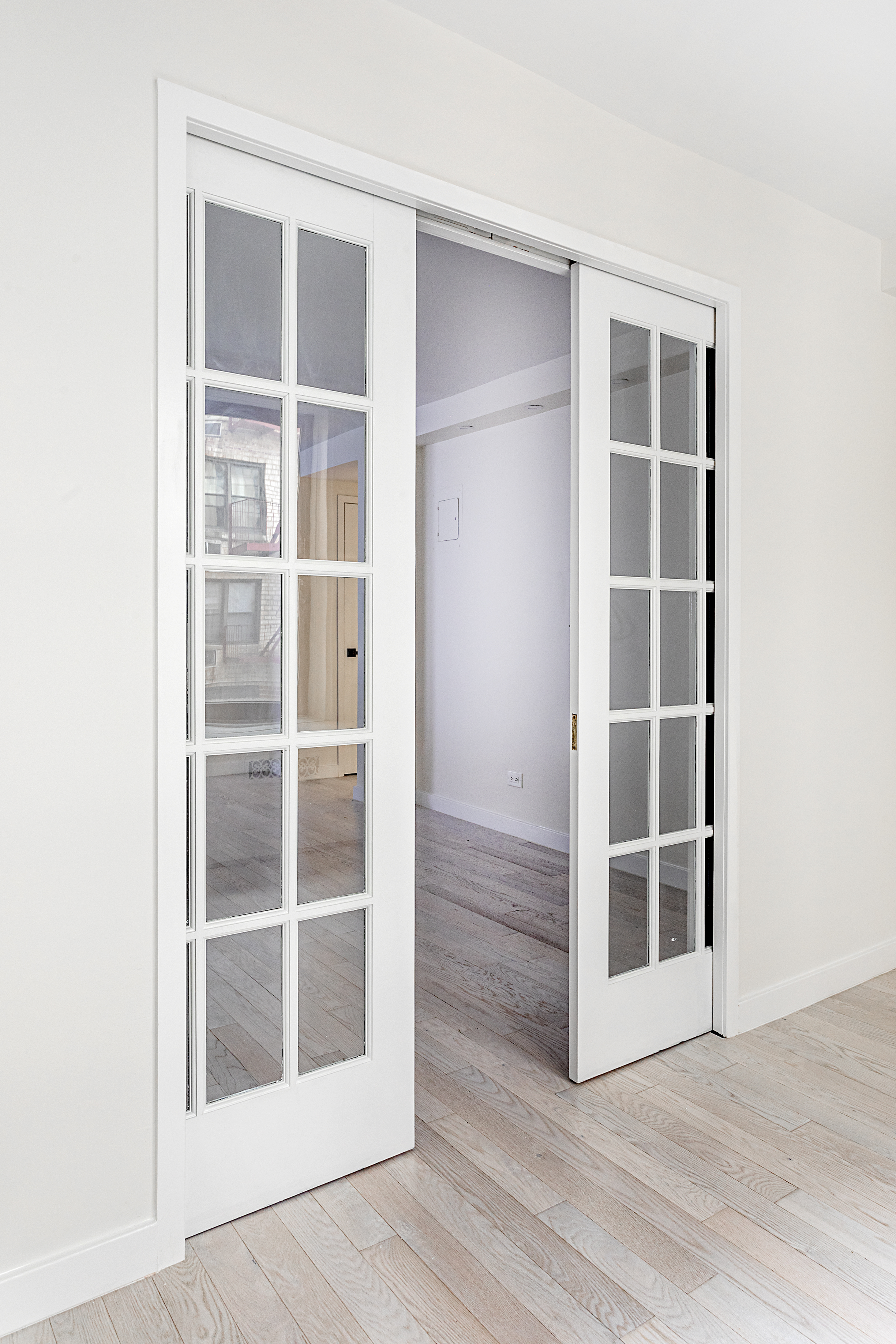 165 Christopher Street, Unit 1C Manhattan, NY 10014 - Photo 5 of 10 a view of an empty room with wooden floor and windows