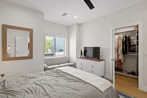 a bedroom with a bed and a flat tv screen on dresser
