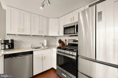 a kitchen with stainless steel appliances white cabinets and a stove top oven