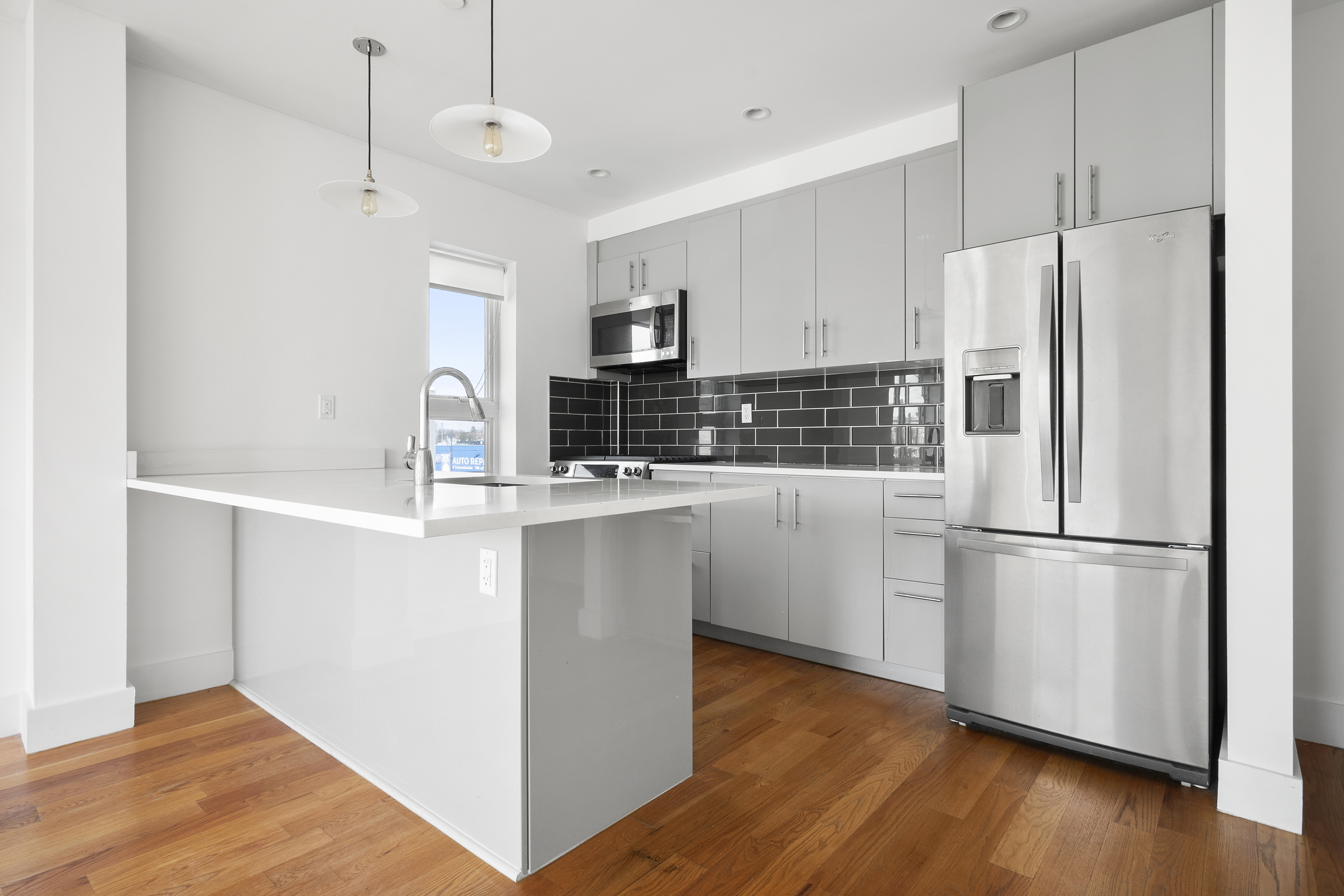 63-34 Fresh Pond Road, Unit 3D Queens, NY 11385 - Photo 4 of 14 a kitchen with kitchen island white cabinets and wooden floor