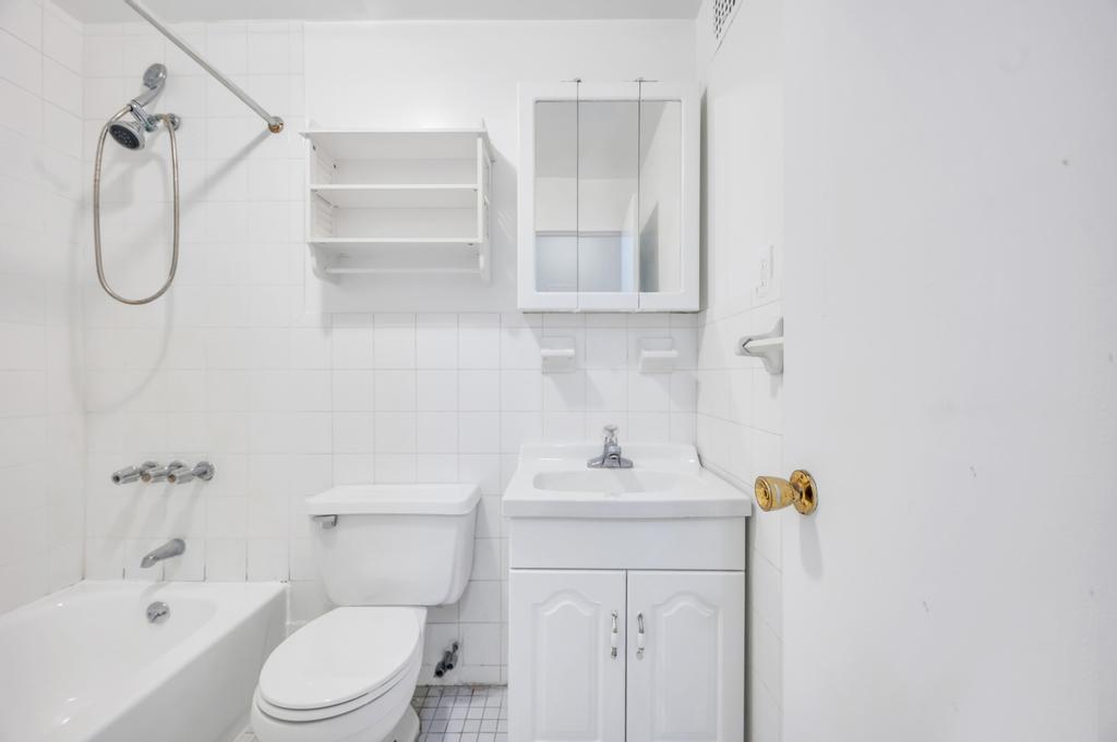 344 West 49th Street, Unit 4B Manhattan, NY 10019 - Photo 5 of 11 a bathroom with a toilet sink vanity and tub