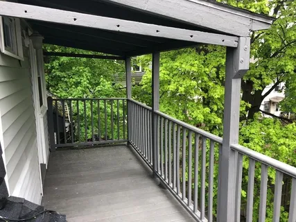 a view of a porch with wooden floor in front of a yard