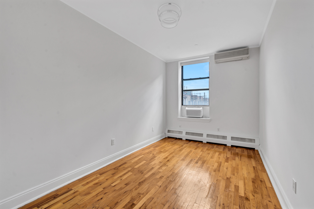 2098 Frederick Douglass Boulevard, Unit 5E Manhattan, NY 10026 - Photo 6 of 8 a view of empty room with wooden floor and fan