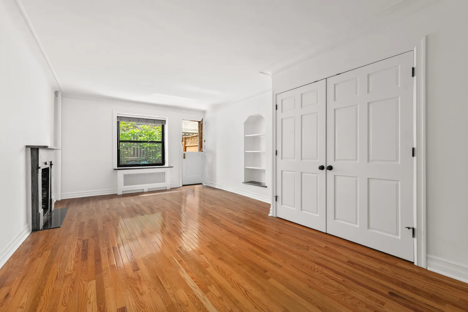 a view of an empty room with window and wooden floor