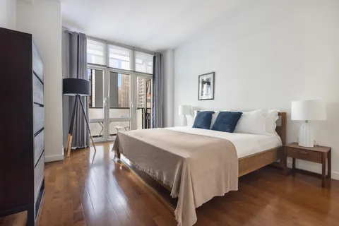 a bedroom with a bed and a large mirror next to a window