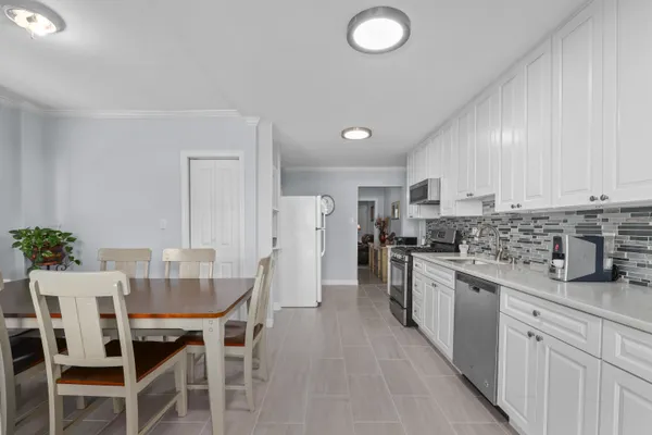 a kitchen with granite countertop a table chairs stove and white cabinets