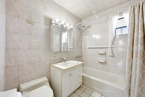 a bathroom with a tub sink vanity granite and a shower