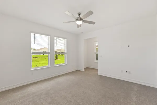 an empty room with window ceiling fan and couch