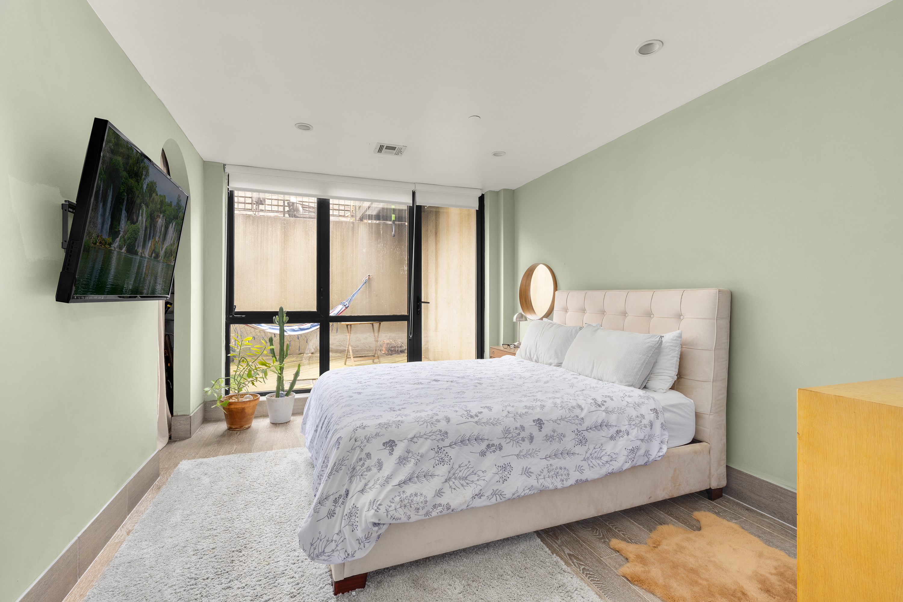 729 Decatur Street, Unit 1 Brooklyn, NY 11233 - Photo 4 of 7 a bedroom with a large bed and a flat tv screen on dresser