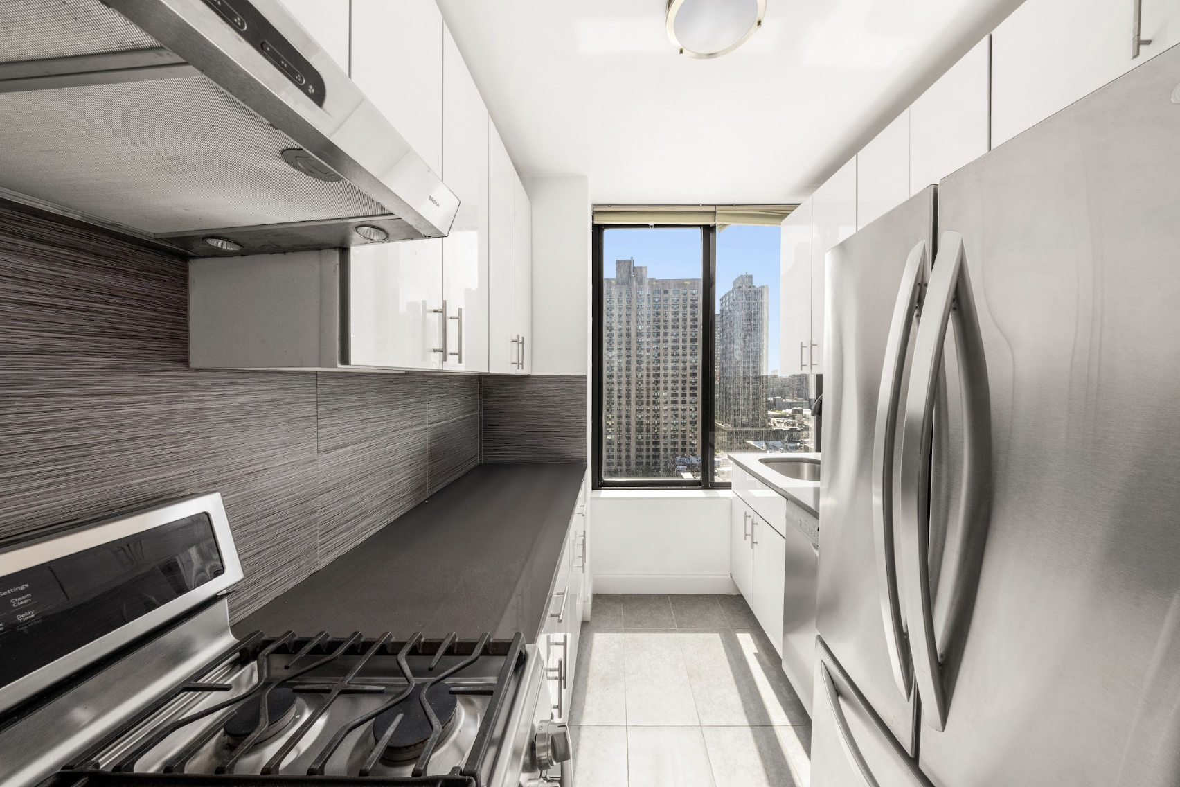 300 East 93rd Street, Unit 18E Manhattan, NY 10128 - Photo 4 of 15 a kitchen with stainless steel appliances a refrigerator and a stove