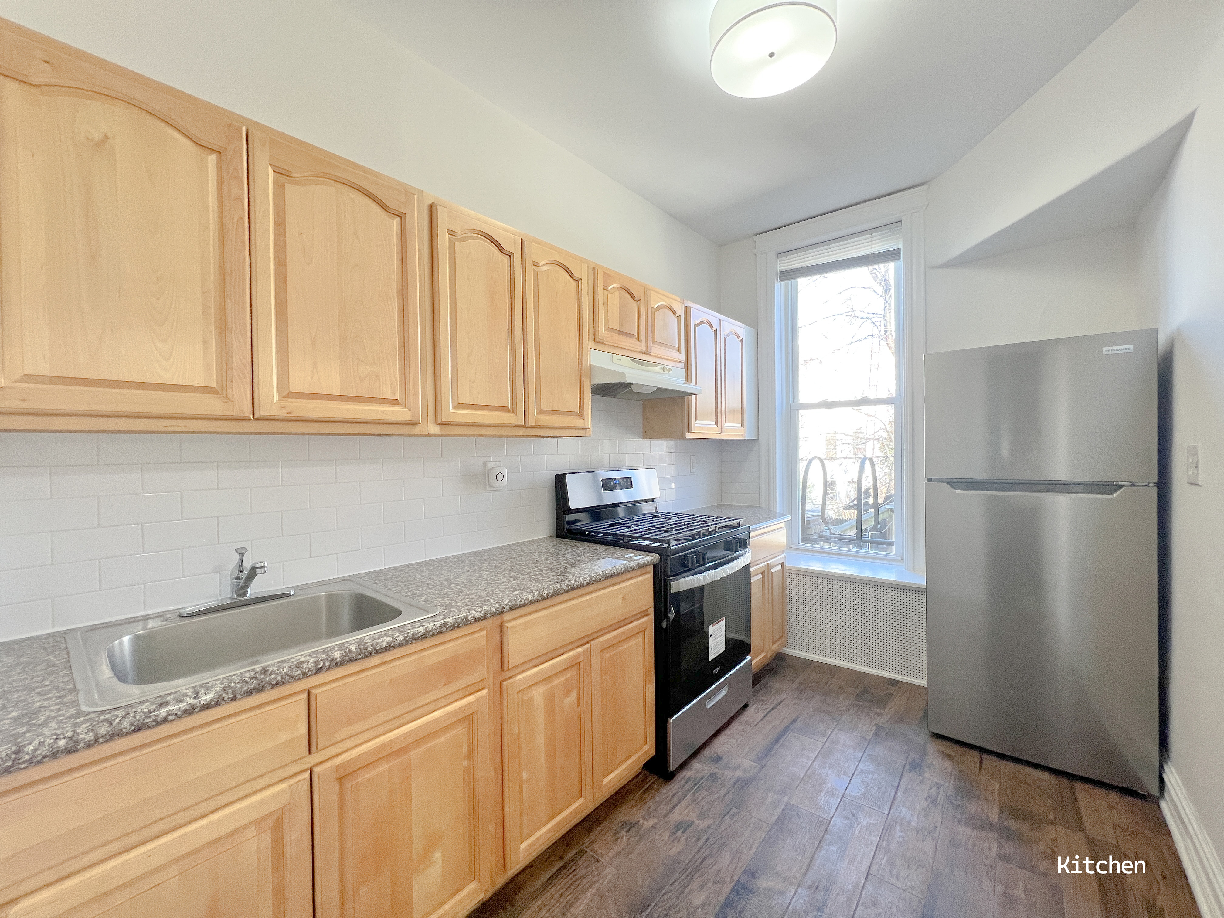 271 71st Street, Unit 2 Brooklyn, NY 11209 - Photo 7 of 10 a kitchen with stainless steel appliances granite countertop a refrigerator sink and cabinets