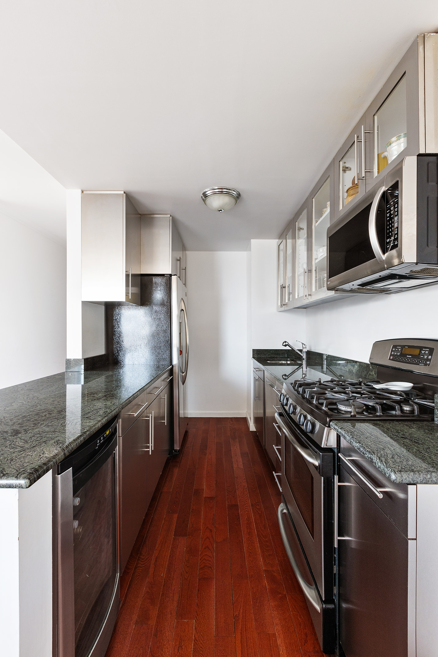 1619 3rd Avenue, Unit 21H Manhattan, NY 10128 - Photo 4 of 16 a kitchen with stainless steel appliances granite countertop a stove a sink and a microwave