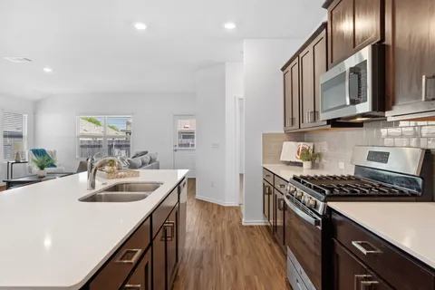 a kitchen with stainless steel appliances granite countertop a sink stove and cabinets