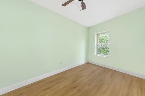 an empty room with ceiling fan and window