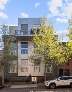 a front view of a building with lot of cars and trees