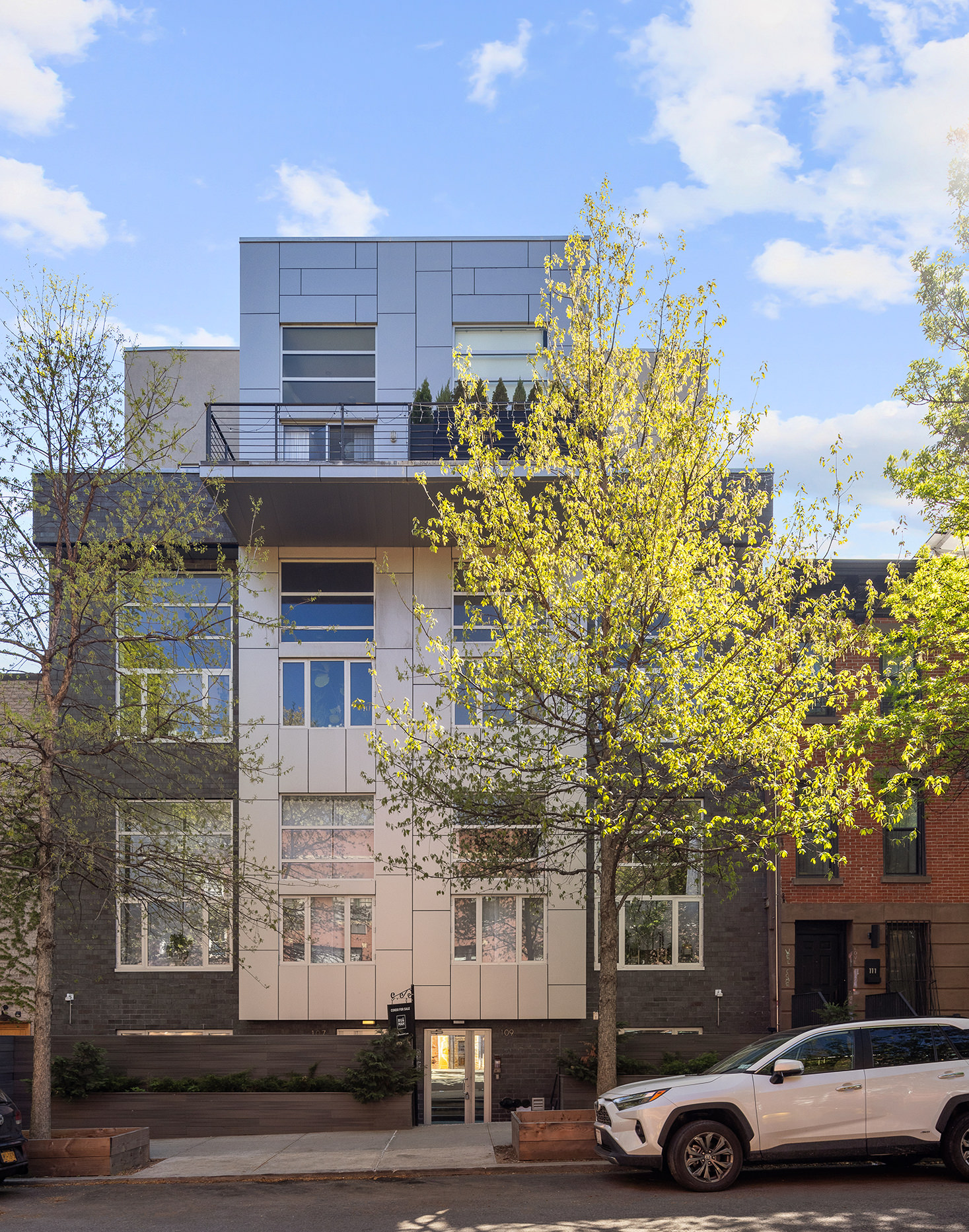 109 Waverly Avenue, Unit 4B Brooklyn, NY 11205 - Photo 8 of 14 a front view of a building with lot of cars and trees