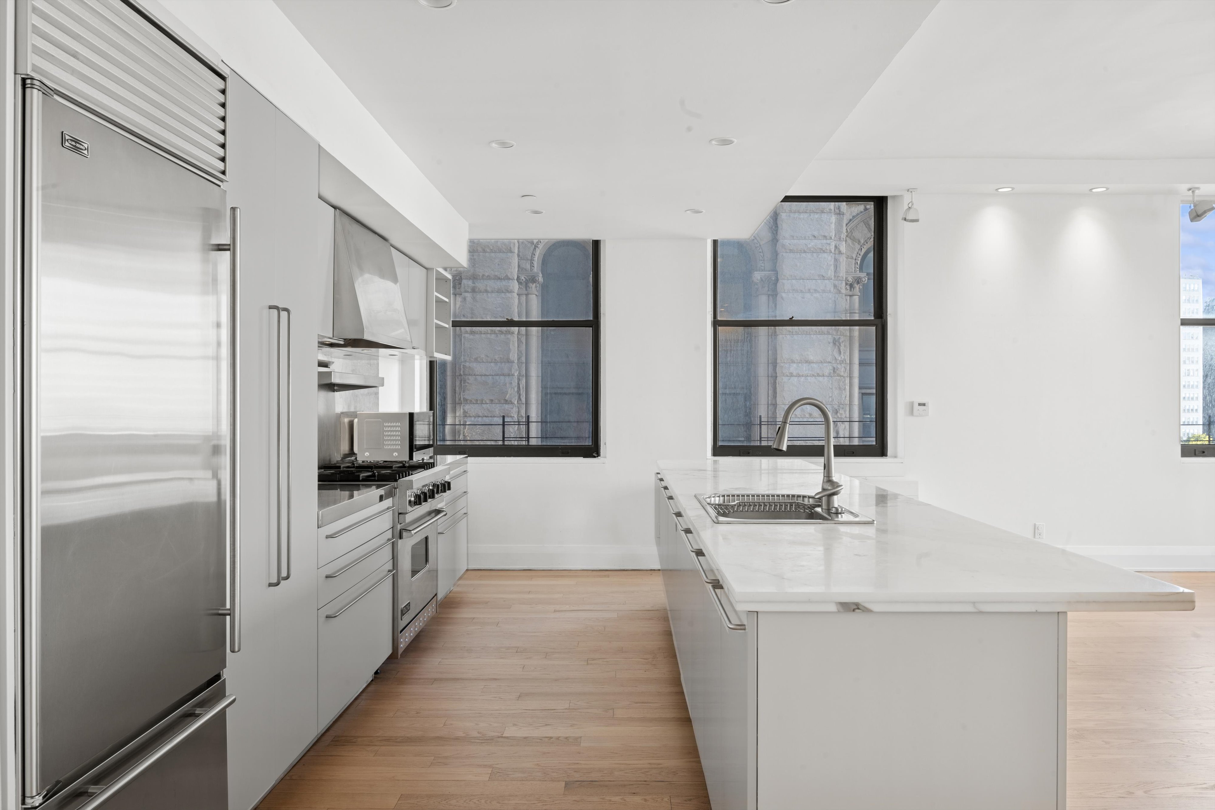 150 Nassau Street, Unit 11B Manhattan, NY 10038 - Photo 4 of 17 a kitchen with white cabinets and stainless steel appliances