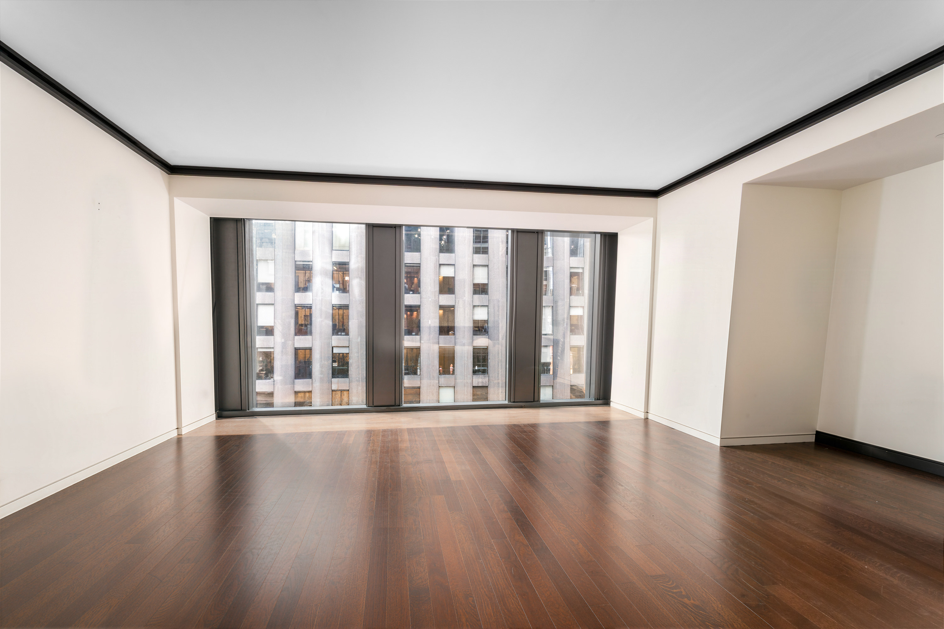 53 West 53rd Street, Unit 20E Manhattan, NY 10019 - Photo 2 of 11 a view of an empty room with wooden floor and a window