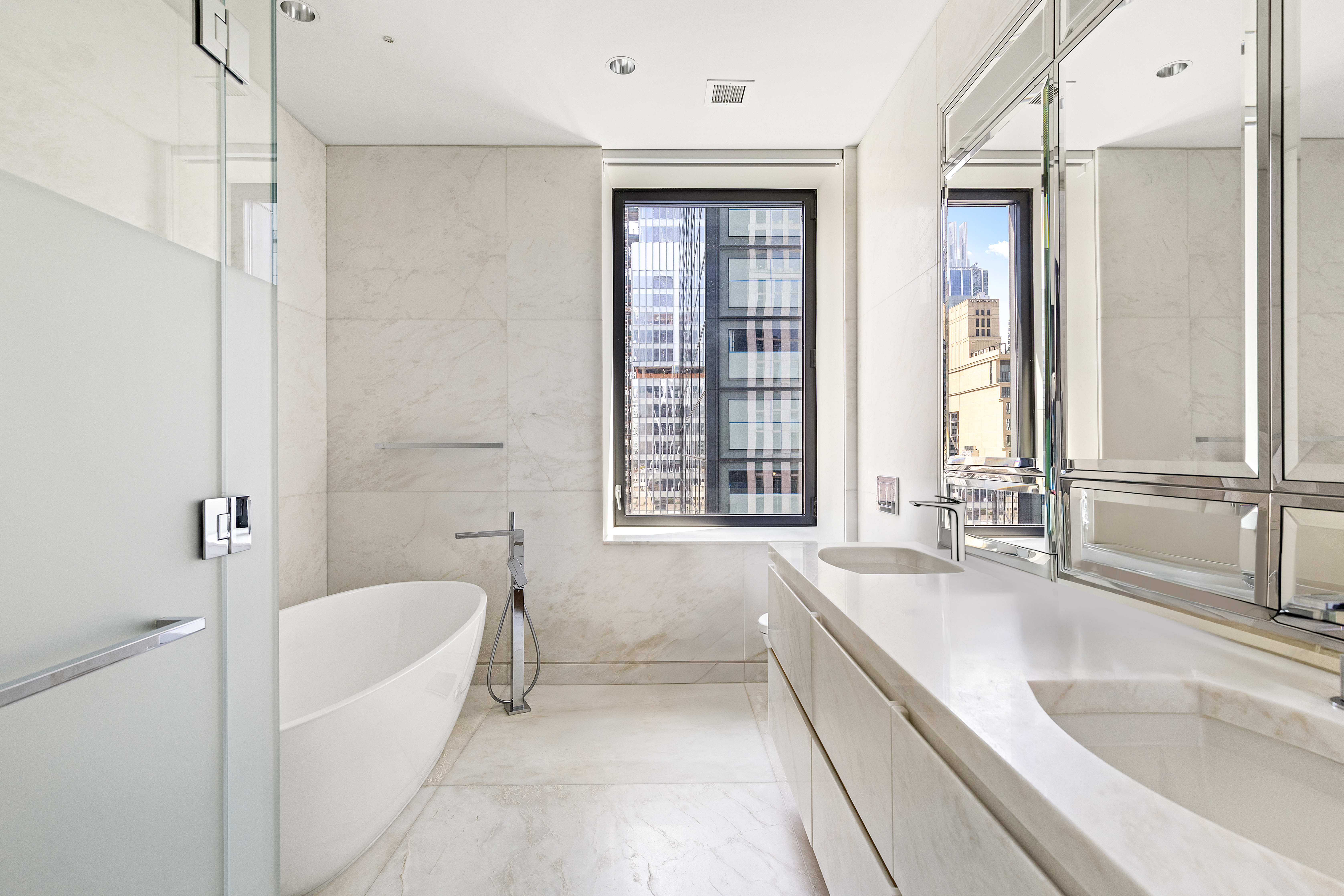 20 West 53rd Street, Unit 22A Manhattan, NY 10019 - Photo 8 of 16 a bathroom with a granite countertop tub sink and mirror