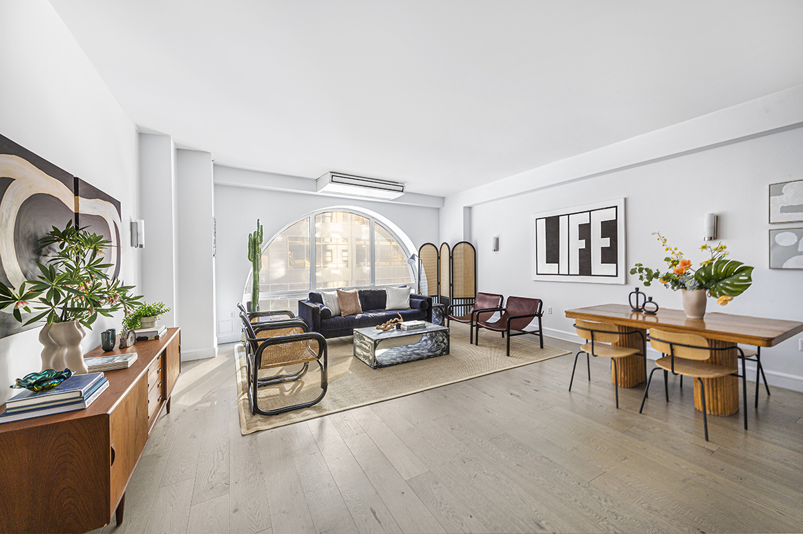 a living room with furniture a potted plant and open kitchen view