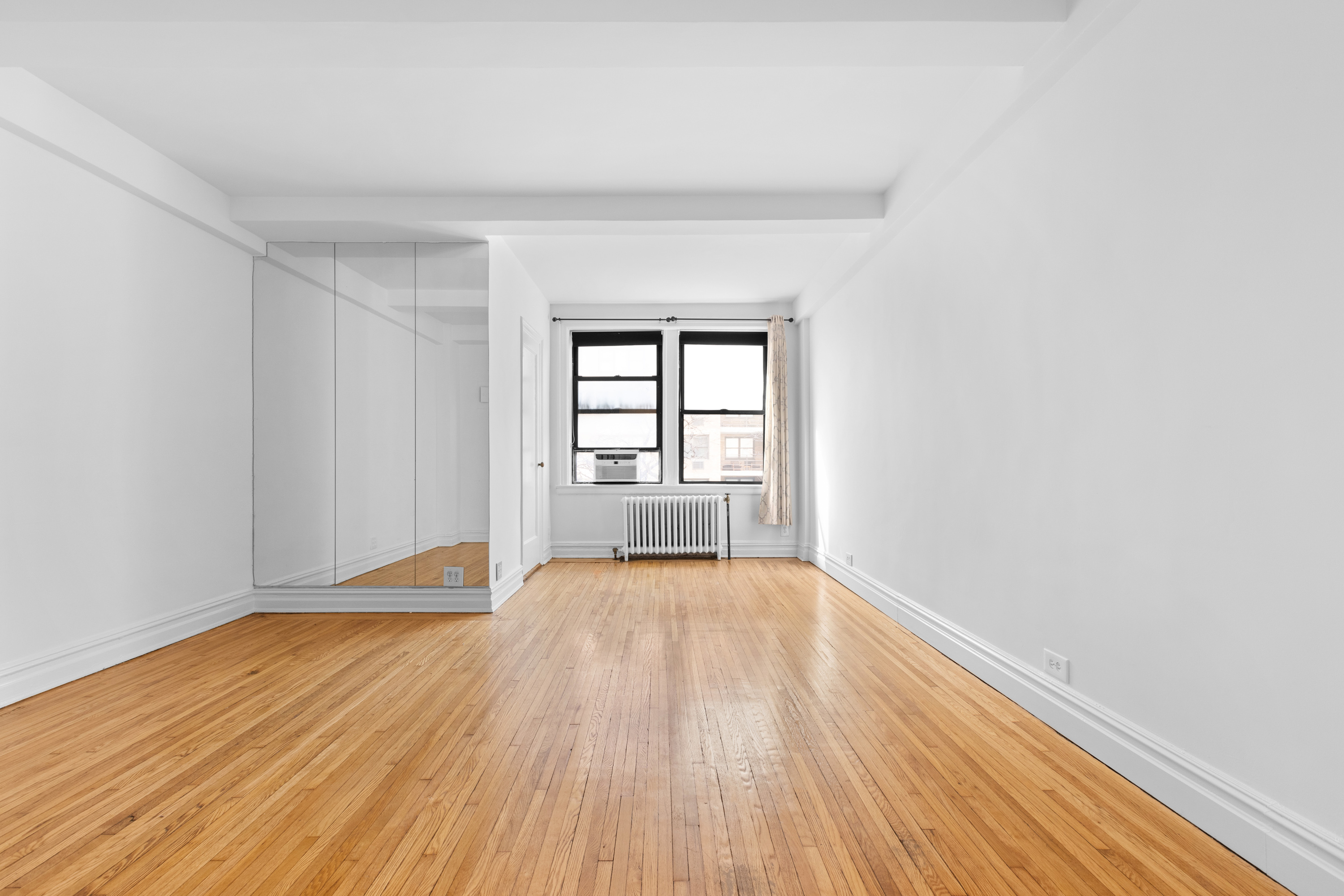 457 West 57th Street, Unit 304 Manhattan, NY 10019 - Photo 3 of 7 wooden floor in an empty room with a window