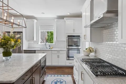 a kitchen with white cabinets and window